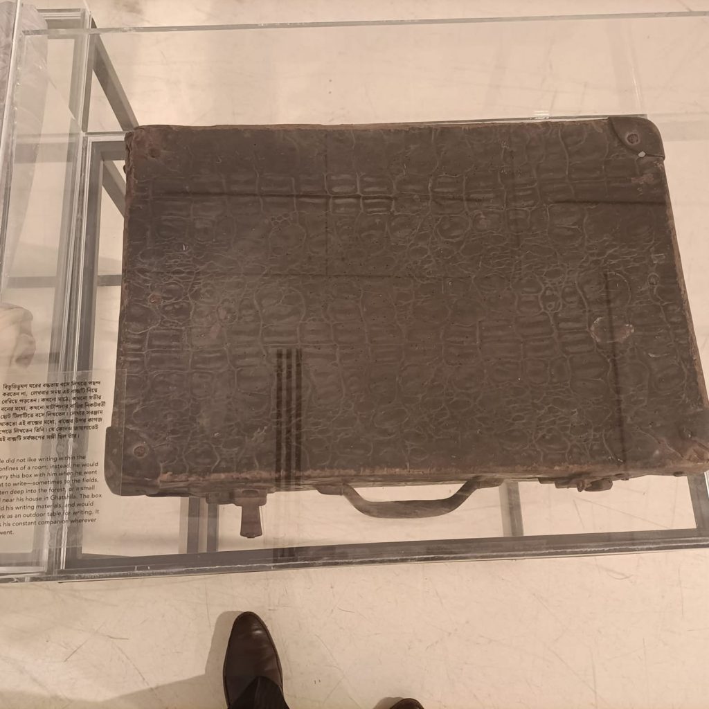 বিভূতিভূষণ-২০। ঘরের বদ্ধতায় লিখতে পছন্দ করতেন। লেখার সময় বাক্সটি নিয়ে বেড়িয়ে পড়তেন। কখনও মাঠে, কখনও গভীর বনের মধ্যে, কখনও ঘাটশিলার বাড়ির নিকটবর্তী ছোট টিলাটিতে বসে লিখতেন। লেখার সরঞ্জাম থাকত এই বাক্সে। এর ওপর কাগজ পেতে তিনি লিখতেন। যে কোনও জায়গায় এটি তাঁর সর্বক্ষণের সঙ্গী ছিল।